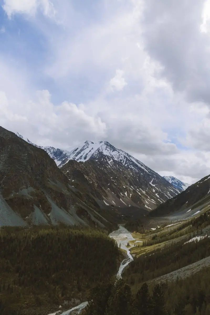 A mountain valley with a river winding toward snow-capped peaks.