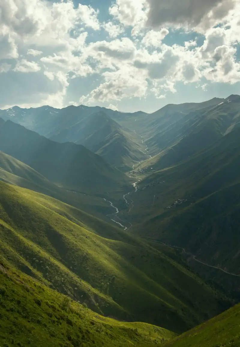 A green mountain valley with a river winding through it.