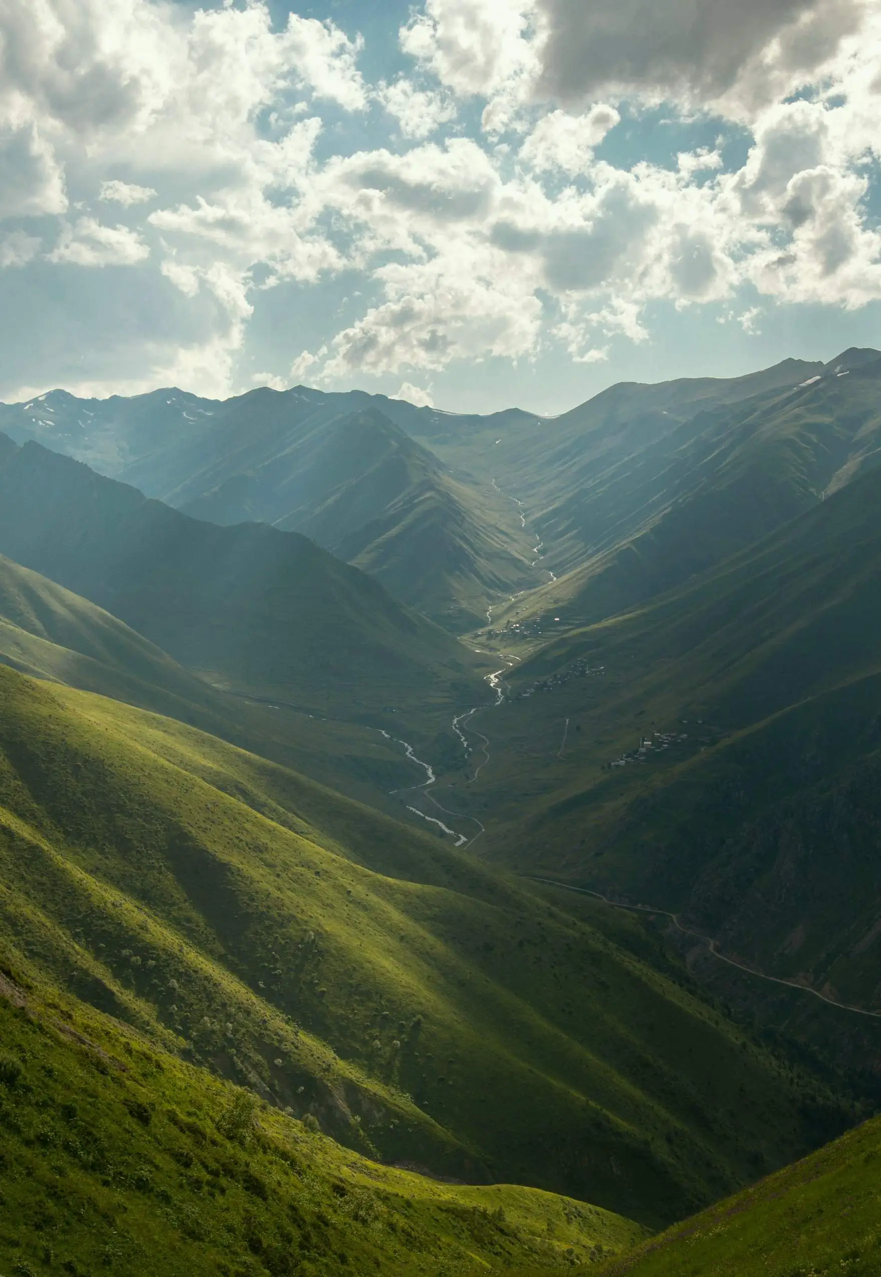 A green mountain valley with a river winding through it.